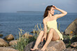 © zhagunov_a - Woman in yellow dress sitting on seaside rocks