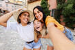 © Xavier Lorenzo - Multiracial young female friends taking selfie outdoors. Happy women capturing memories together while exploring a charming city. Friendship and travel concept.