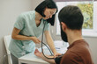 © dsheremeta - Nurse checking male patient's blood pressure in clinic