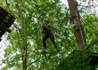 © Stefanie - Teen girl navigating hanging obstacles in forest high ropes course