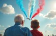 © miss irine - Old man and boy watch airshow with planes releasing red blue white smoke. Family watches aviation performance outdoors, enjoying event. Shared moment, sky watching, summer day.