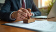 © miss irine - Lawyer stamps document with wooden seal, confirming contract. Person uses rubber stamp for official paperwork, legal approval, and agreement.