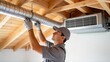 © Alicia - Man installing air duct in wooden ceiling