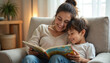 © Pete - Mother and son smile while reading storybook together in comfy chair. Parent shares tale, child listens attentively. Cozy indoor scene depicts family bonding and early literacy.