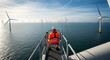 © tu - Professional technician in bright orange protective gear sitting on an offshore wind turbine platform overlooking the vast blue ocean at a renewable energy farm during routine inspection