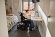 © PintoArt - Young woman using electric wheelchair working from home