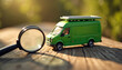 © Viktor - Miniature green delivery van with solar panel sits on wooden surface near magnifying glass. Examining eco friendly transport concept for future logistics and urban freight.