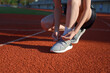 © Prathankarnpap - Close up of woman tying running shoe laces on outdoor track before exercise, fitness preparation