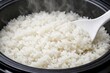 © Jumpei - 炊飯器の中でふっくらと炊き上がった湯気が立つ真っ白なご飯をしゃもじですくう様子