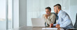 © insta_photos - Happy busy professional team of two business men executive having discussion, male partners working using laptop looking at computer analyzing online tech data at work in office sitting at desk.