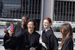 © wavebreak3 - Diverse female graduates in gowns laughing while taking phone selfie at urban plaza with diplomas