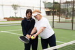 © Angelov - a girl teaches her grandmother how to play padel