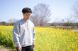 © Masakazu Tokashiki - A man is standing in a field of yellow flowers. The field is full of yellow flowers and the sky is clear