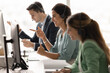 © fizkes - Diverse customer care team sitting at desk in headsets communicating online via computers managing client relationships handling inquiries providing professional friendly service in call centre office