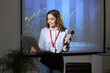 © Pixel-Shot - Female business speaker with laptop conducting seminar near projector screen in office