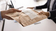 © fizkes - Office delivery handover. Close up 2 businessmen hands give receive small paper postal package with label. Express mail transportation service document exchange delivering parcel to addressee concept