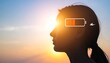 © delvina - Silhouette of a womans head against a sunset with a low battery symbol superimposed, symbolizing mental fatigue or low energy levels.