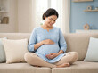 © Someone Cooked Here - indian pregnant woman sitting cross legged on sofa in powder blue maternity kurti representing prenatal wellness maternal healthcare and maternity insurance campaign concept