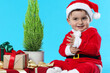 © New Africa - Cute baby with potted thuja tree and Christmas gifts on light blue background