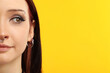 © New Africa - Beautiful young woman with different face piercings on yellow background, closeup. Space for text