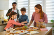© djile - Family preparing breakfast together in home kitchen