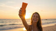 © Natalia - A woman holds a sunscreen bottle on a beach at sunset, skin protection, summer beauty, golden hour wellness.
