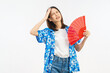 © sitthiphong - Young Asian woman feeling hot and tired while holding a red hand fan and touching her forehead on white background.