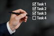 © ATIKUL ISLAM - Hand holding pen marking tasks on a checklist, representing business progress, completion, and successful planning