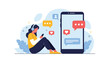 © Natalia - Young woman sits comfortably and uses her smartphone for social media and messaging with headphones on against a blue background.