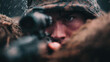 © Julia - Soldier behind sandbags in a foxhole checking a rifle scope in rain in a close up with helmet and uniform on a battlefield with soft light