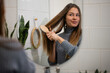 © Zoran Jesic - Young woman brushing long brown hair in bathroom
