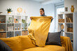 © Zoran Jesic - Woman folding yellow blanket on living room sofa