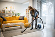 © Zoran Jesic - Woman vacuuming living room carpet for home hygiene