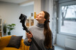 © Zoran Jesic - Woman singing into vacuum cleaner while cleaning home