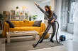 © Zoran Jesic - Woman cheerfully vacuuming living room floor and dancing