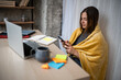 © Zoran Jesic - Woman working remotely at home office wrapped in blanket