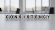 © Md - Consistency text on cubes in a bright, modern office setting representing business success