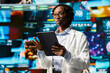 © DC Studio - Scientist analyzing viruses on tablet to support vaccine development, surrounded by medical interfaces videowall backdrop. Doctor reviewing viral mutation models using device app