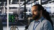 © DC Studio - Smiling data center technician using PC to monitor neural network AI LLM visualization. Server room worker using computer to oversee rigs powering machine learning processes, camera A
