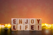 © SimpleDesignStudio - Positive affirmation enjoy life on wooden cubes with warm heart bokeh lights for mental wellness
