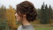 © buraratn - Elegant woman with beautiful updo hairstyle in a serene autumn landscape featuring vibrant leaves and greenery