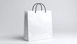 © Endah - A white paper bag with black handles is against a gradient white background. The bag is empty and pristine