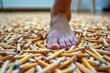 © kornc - A bare foot is stepping on numerous wooden matchsticks scattered on the floor.