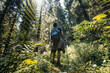 © olezzo - Female hiker with backpack and trekking poles walking through a lush mountain forest.