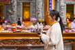 © leungchopan - Devoted woman praying quietly inside asian temple
