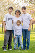 © Tomsickova - Portrait of cute stylish smiling family, boys and grandmother sitting in the grass in park
