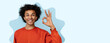© Prostock-studio - A young man smiles and holds up his hand to show the okay sign. The background is a smooth light color, creating a fun and engaging look. The collage style adds a layer of creativity.
