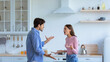 © Prostock-studio - A couple stands in a modern kitchen arguing with each other. The man gestures with his hands while the woman raises her voice. Their expressions show frustration and conflict.