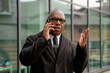 © Iryna - Businessman talks on the phone while standing outside a modern building in a city setting