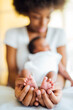 © Westend61 - Close-up of mother carrying newborn daughter on bed at home